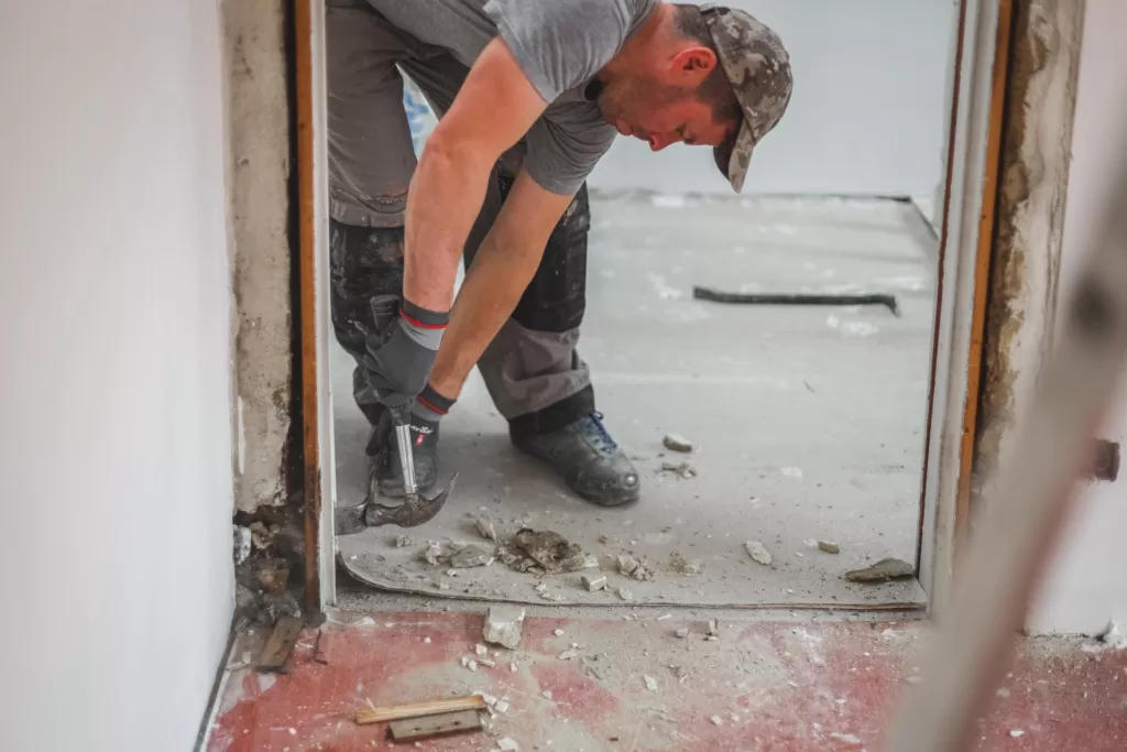 a contractor dismantles the plinth using a hammer and dispose it