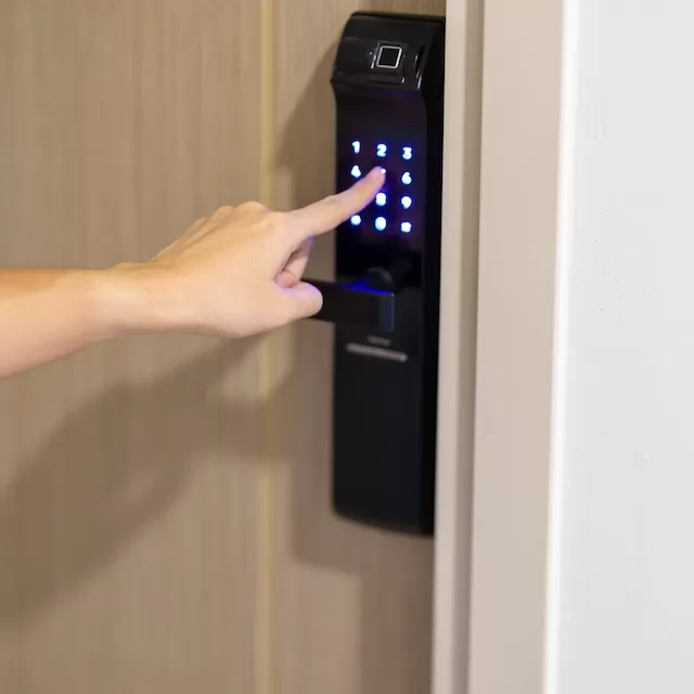 a man key in password on brown door's digital door lock