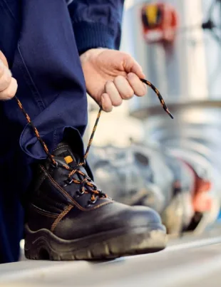 man tying shoelace of his Caterpillar Safety Shoes