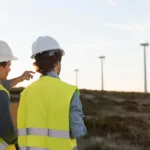 Two men looking and pointing at windmills