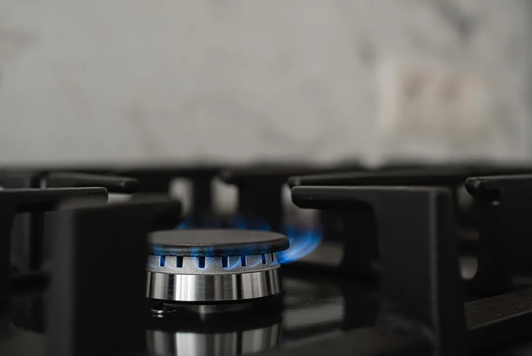 close-up of a gas burner with blue flame on a stove