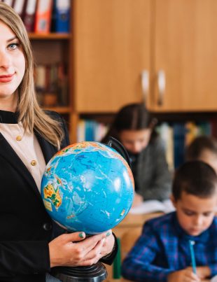 a teacher holding a globe in an international school