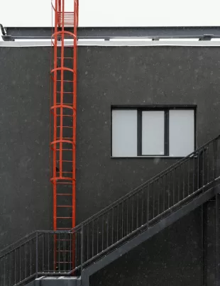 red galvanized cable ladder on the side of a black building