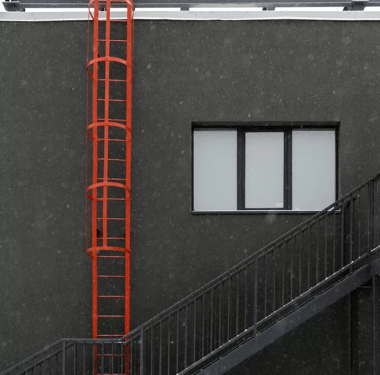 red galvanized cable ladder on the side of a black building