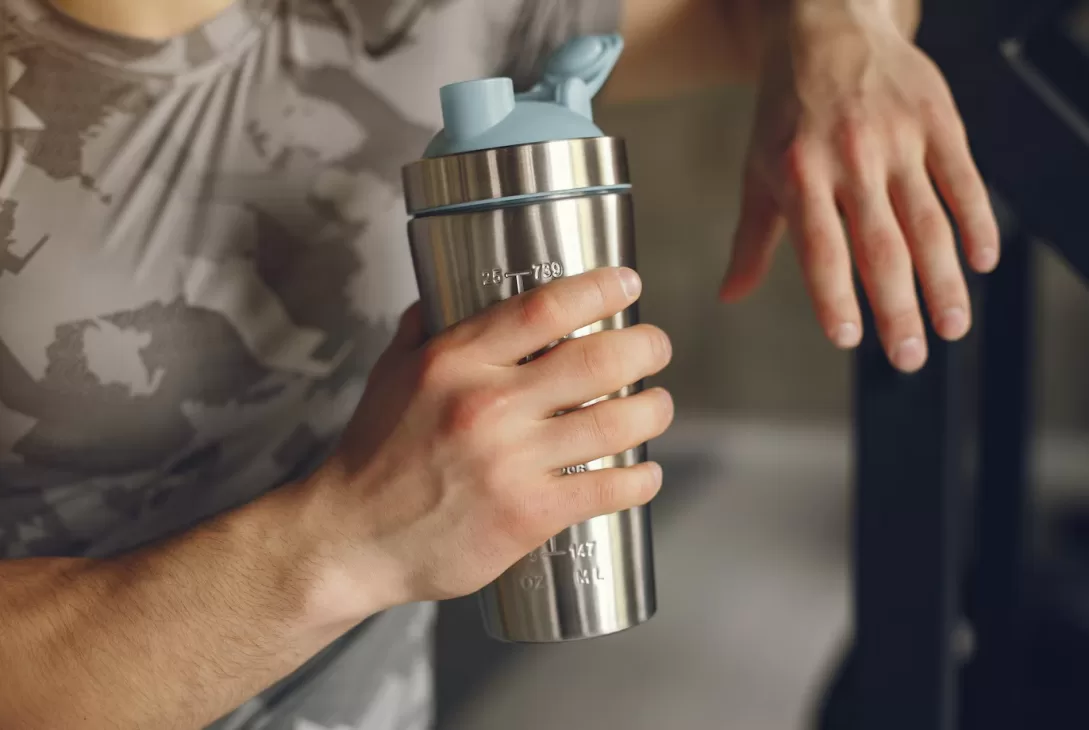 man holding an ergonomic sports water bottle after a workout
