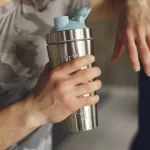 man holding an ergonomic sports water bottle after a workout