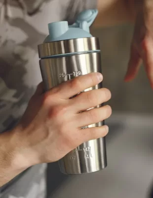 man holding an ergonomic sports water bottle after a workout