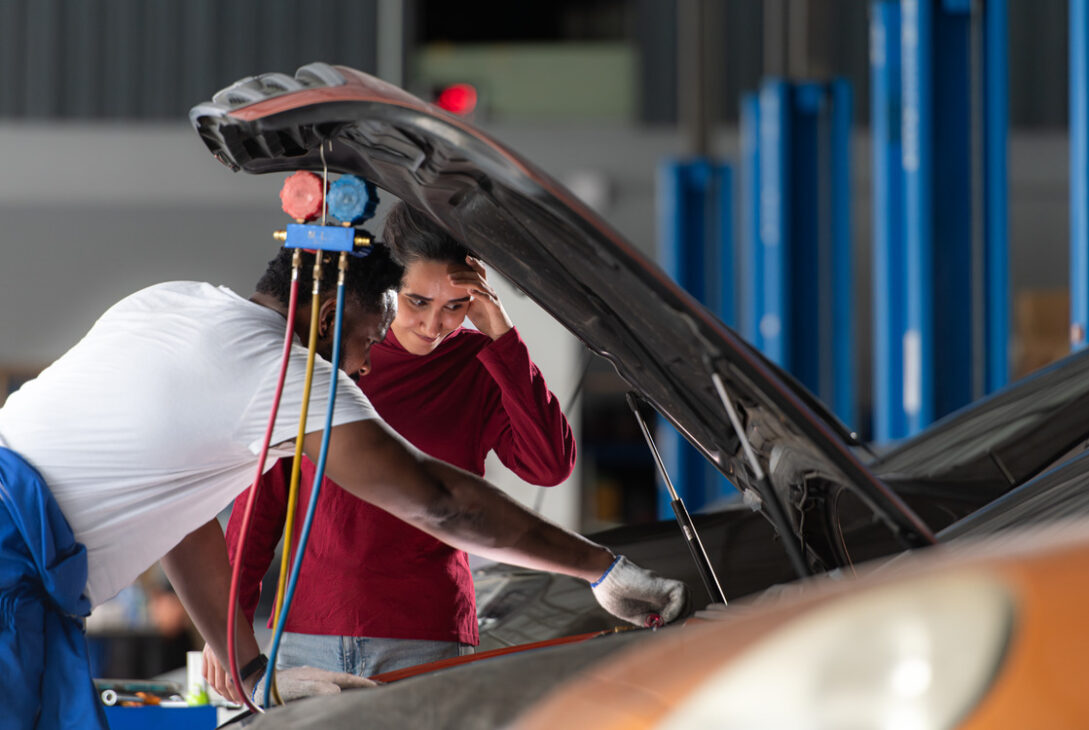 A professional mechanic inspects the Honda car battery whilst explaining its condition to the vehicle owner.