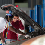 A professional mechanic inspects the Honda car battery whilst explaining its condition to the vehicle owner.