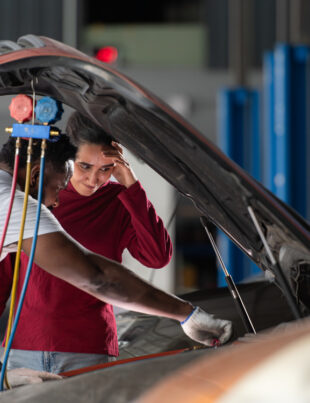 A professional mechanic inspects the Honda car battery whilst explaining its condition to the vehicle owner.