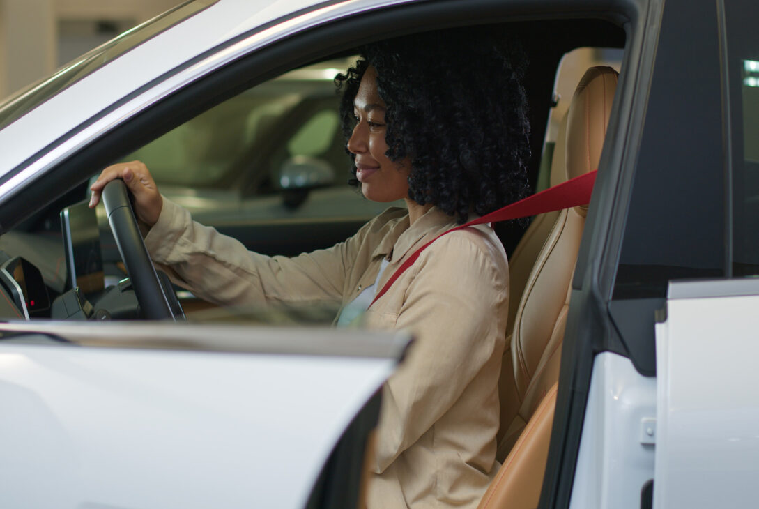 A woman evaluating the battery Perodua Bezza car performance during a test drive.
