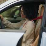 A woman evaluating the battery Perodua Bezza car performance during a test drive.