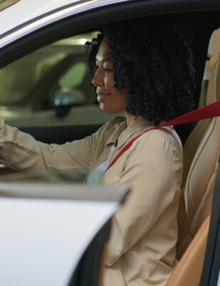 A woman evaluating the battery Perodua Bezza car performance during a test drive.