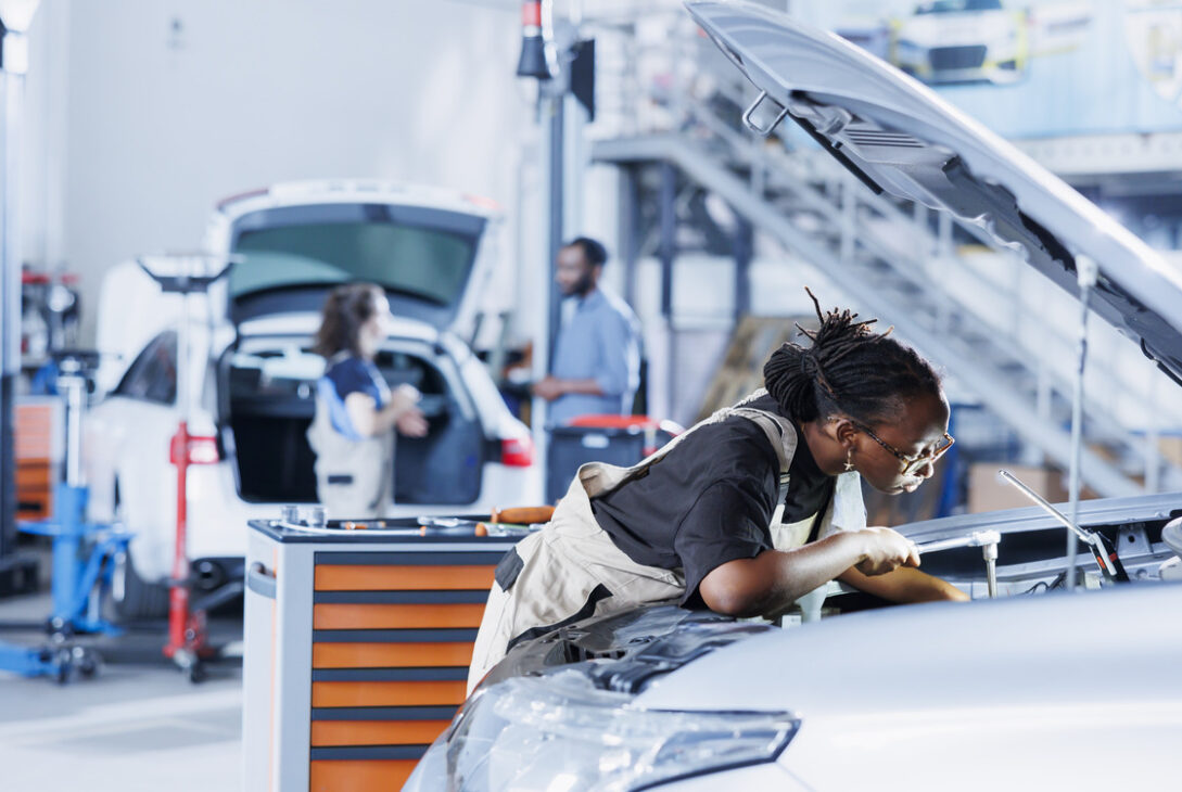 A professional mechanic expertly replacing a BMW car battery in a workshop.