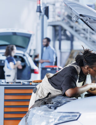 A professional mechanic expertly replacing a BMW car battery in a workshop.