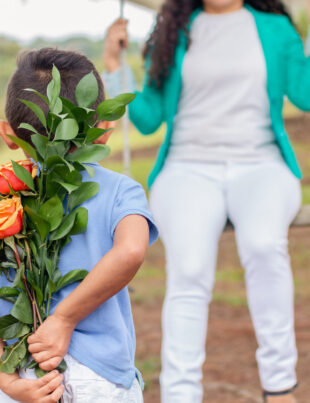 A boy discreetly hiding a beautiful flower bouquet to surprise his mom for Mother's Day.