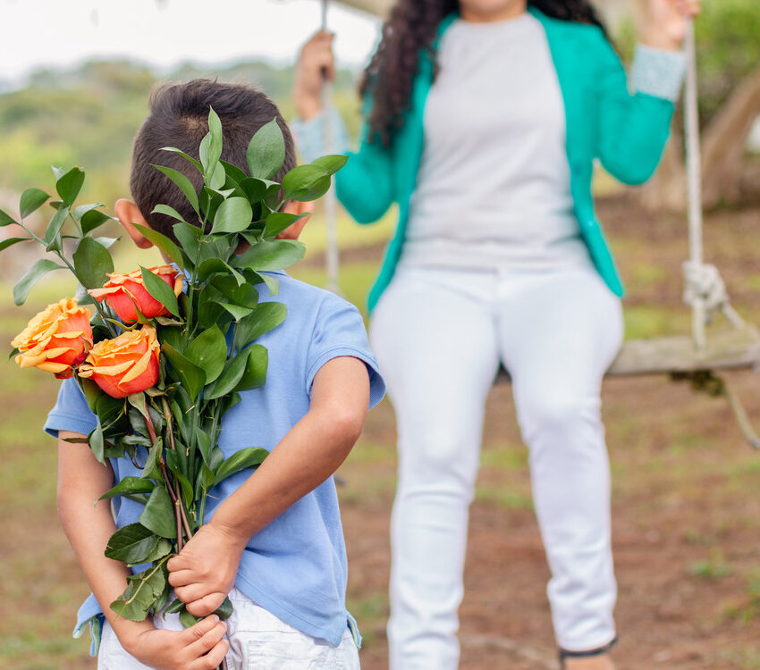 A boy discreetly hiding a beautiful flower bouquet to surprise his mom for Mother's Day.