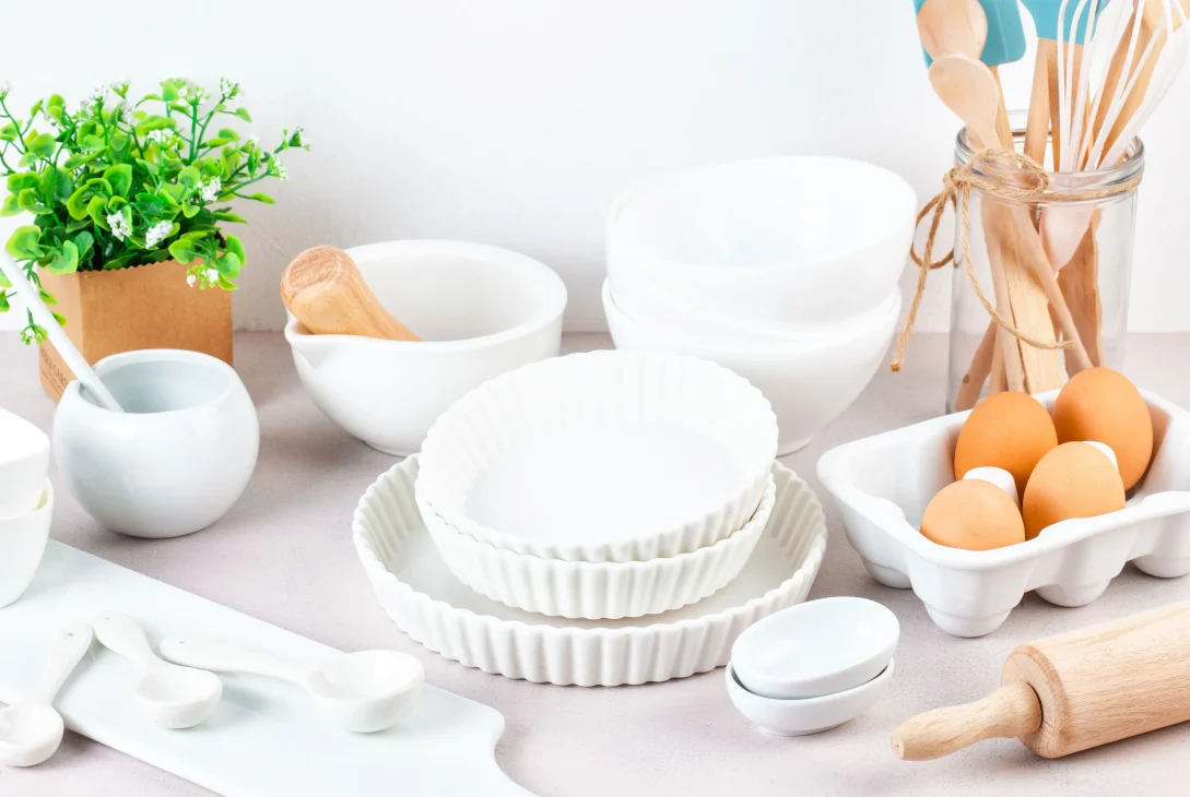 Aesthetic white kitchenware set with matching bowls, dinner plates, utensils, and cutlery tools on a clean countertop
