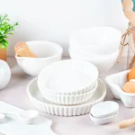 Aesthetic white kitchenware set with matching bowls, dinner plates, utensils, and cutlery tools on a clean countertop