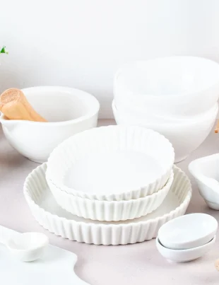 Aesthetic white kitchenware set with matching bowls, dinner plates, utensils, and cutlery tools on a clean countertop
