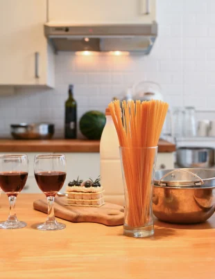 Cozy kitchen scene with glassware and cooking utensils on a wooden countertop.
