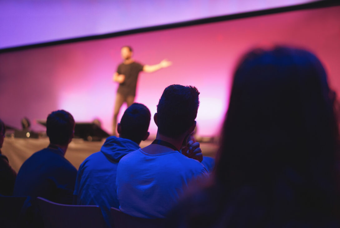 Audience watching a keynote speaker present on stage at a conference in Singapore