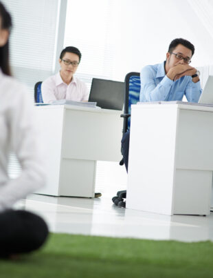 Employee meditating in an office setting while coworkers observe, representing a mental wellness program in a Singapore workplace