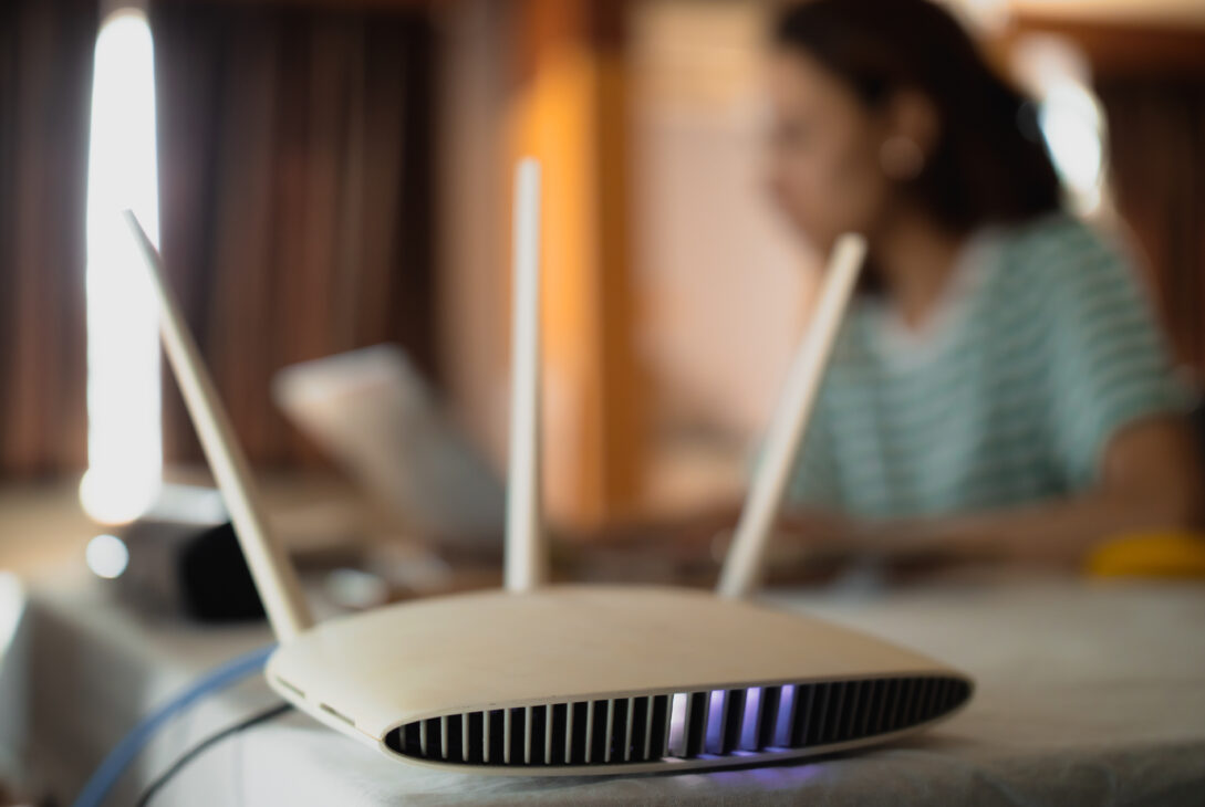 WiFi router on table with woman working on laptop in the background