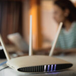 WiFi router on table with woman working on laptop in the background