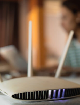 WiFi router on table with woman working on laptop in the background