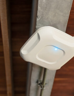 Person holding a WiFi router surrounded by laptops and smartphones on a desk